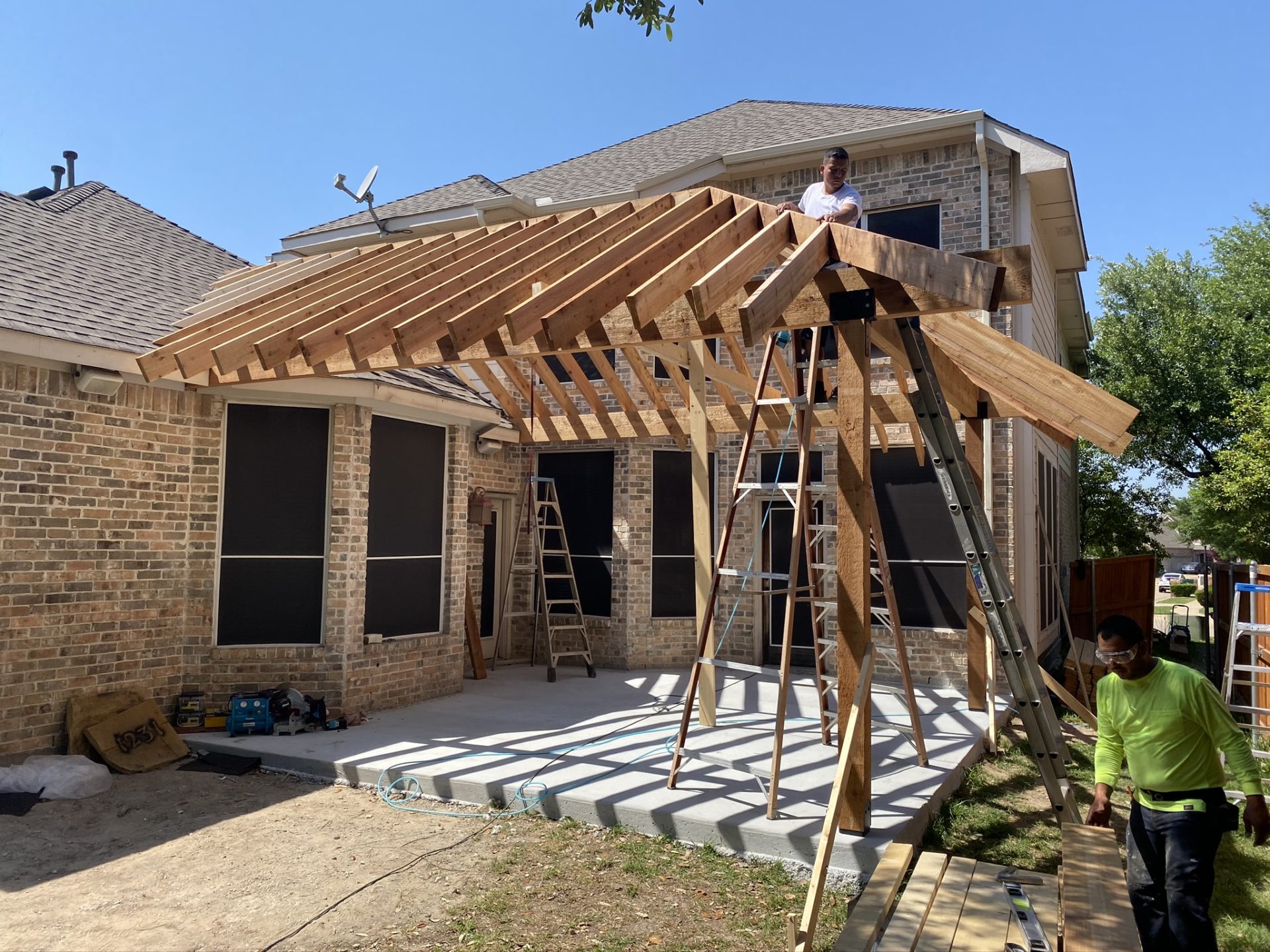 Jenkins Roofing workers building pavilion patio cover that extends home in Arlington, TX