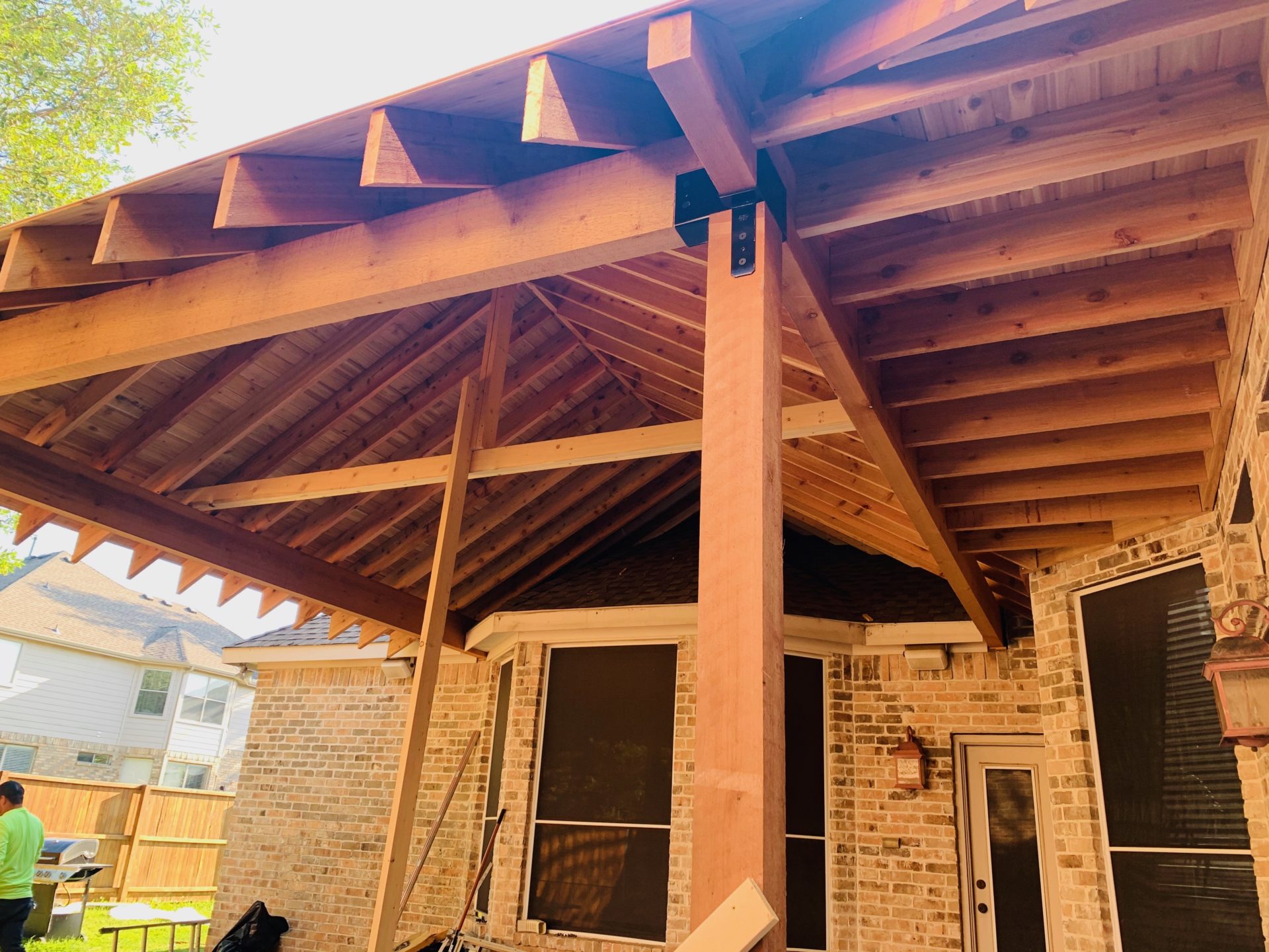 Underside of pavilion patio roof with fresh wooden crossbeams that extends home.