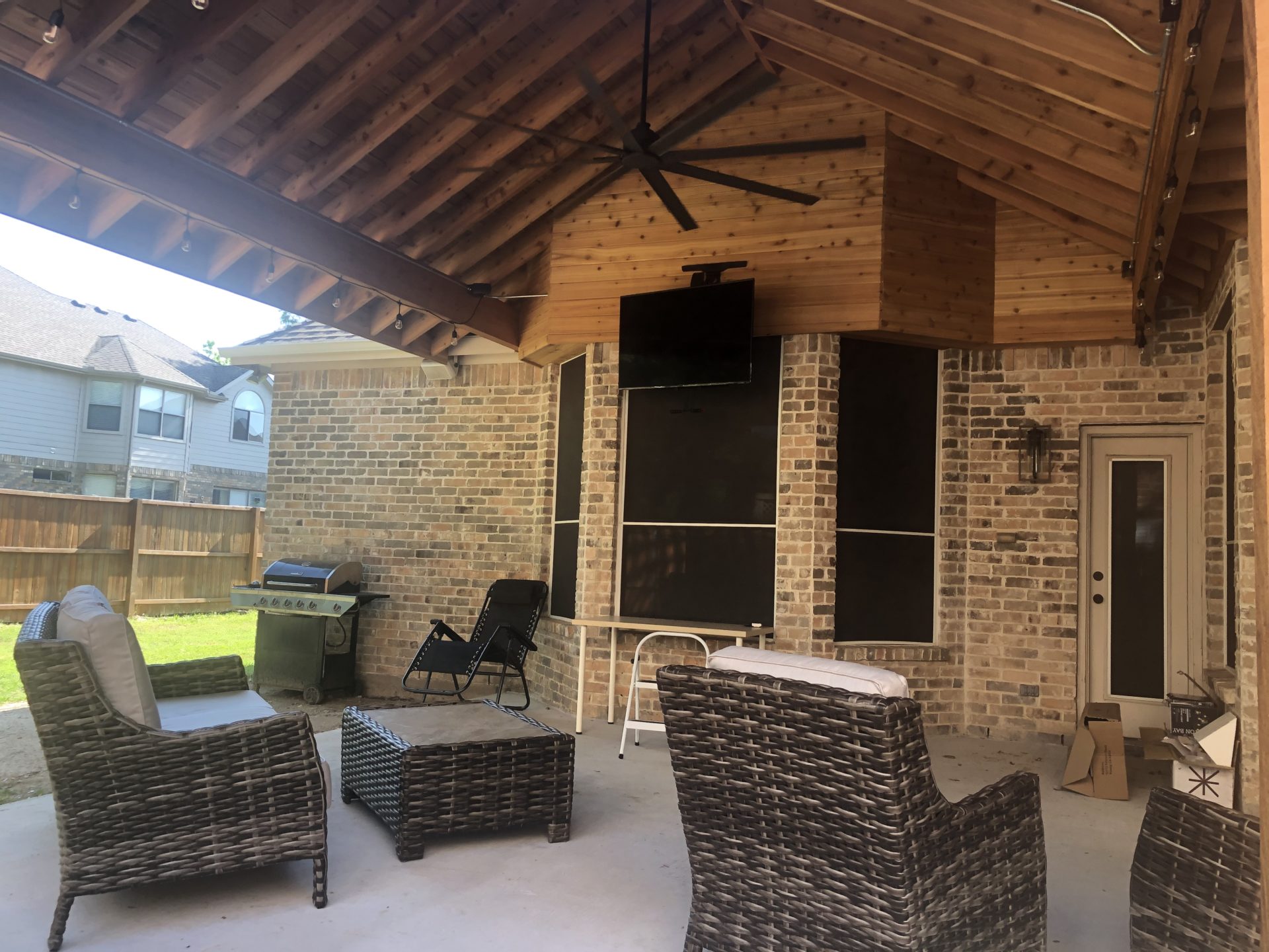 Finished outdoor patio with Pavilion style roof that extends home in Dallas Fort Worth's outdoor living space. Patio installation includes outdoor ceiling fan, tv, patio furniture, and more.