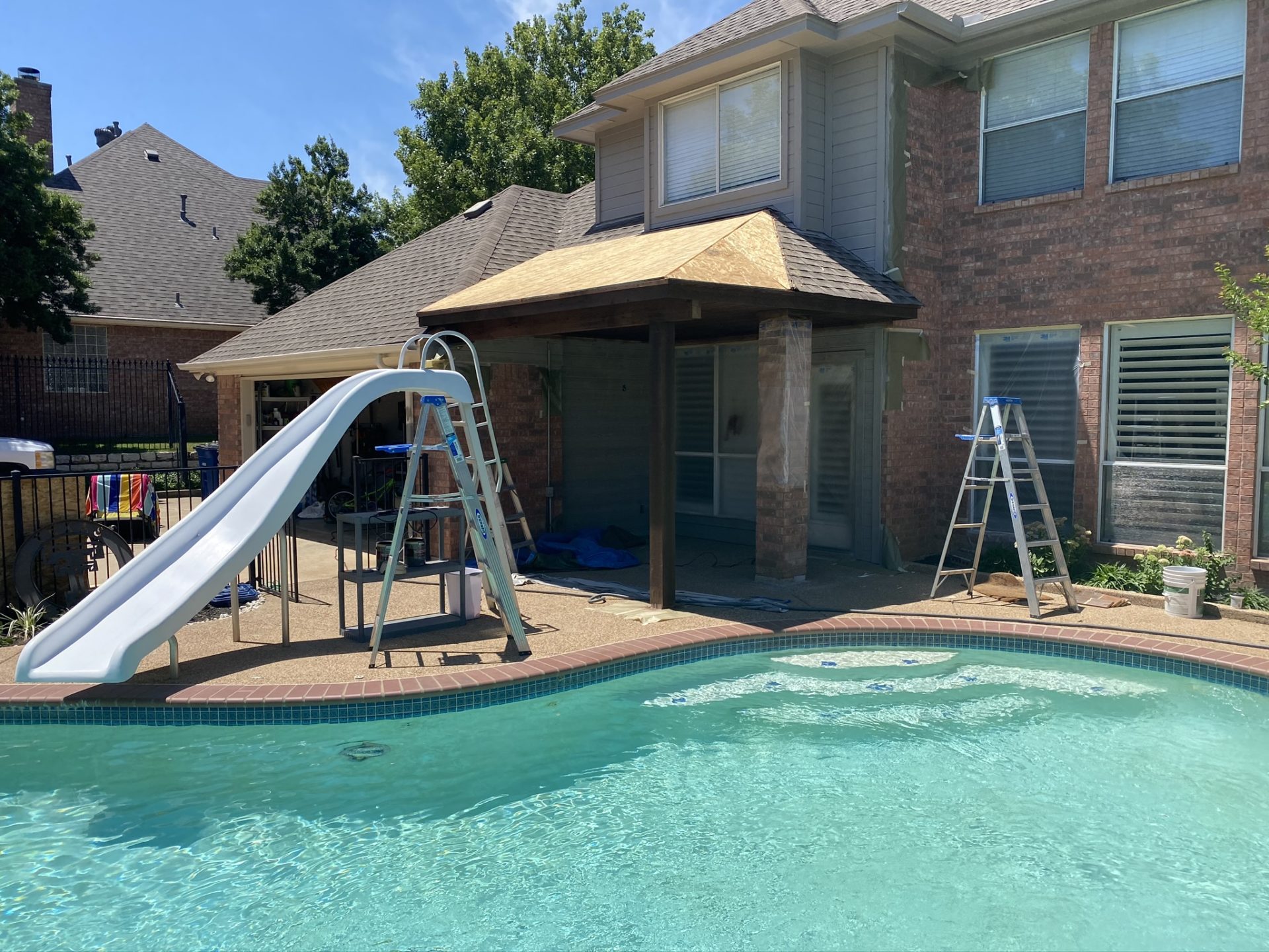 Home in Dallas-Fort Worth Texas, showing the backyard area with pool and extended roof cover built by Jenkins Roofing.