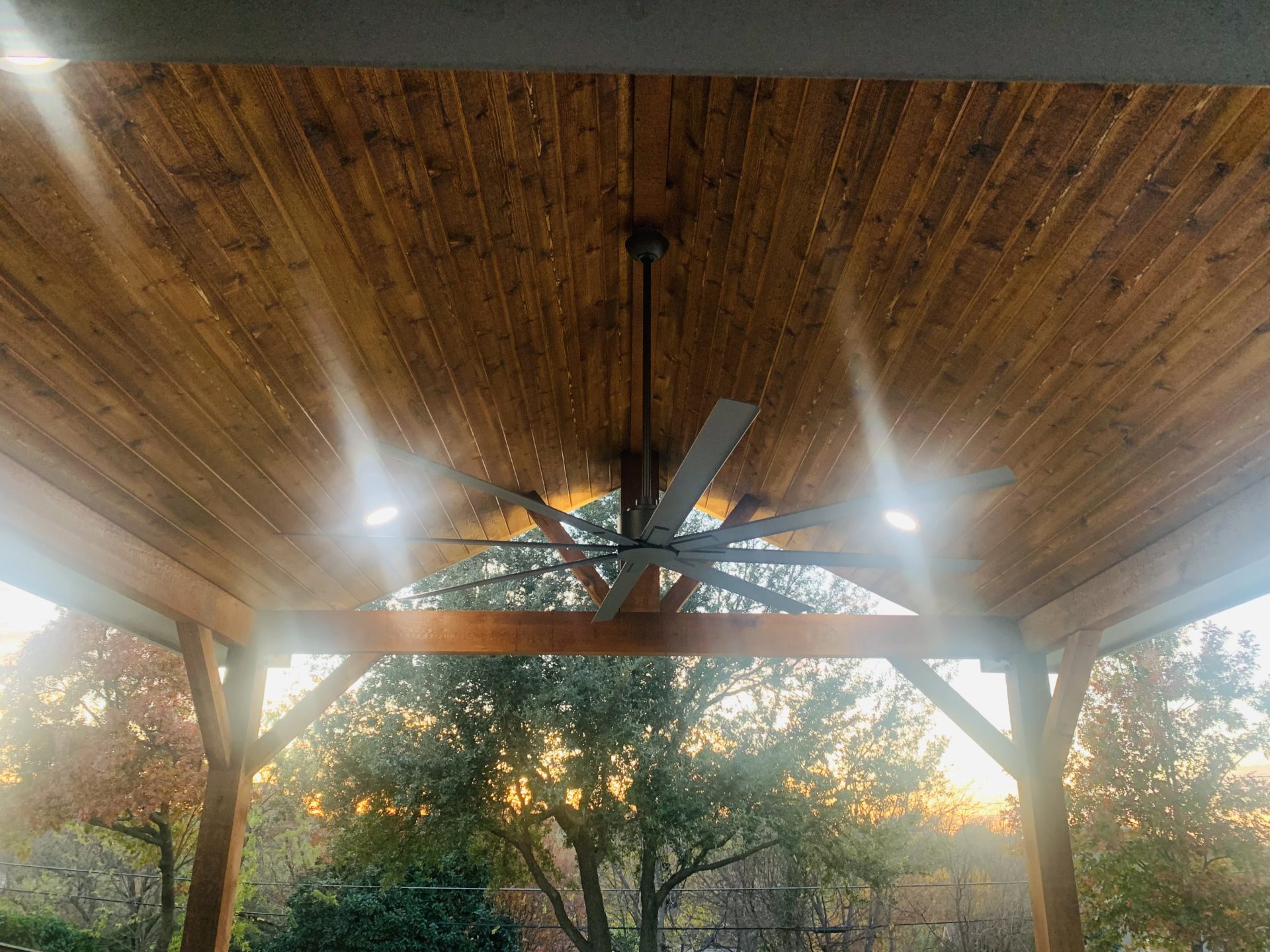 Outdoor patio project by Jenkins Roofing with roof extending from the house, large outdoor ceiling fan and custom patio lights in wooden roof.