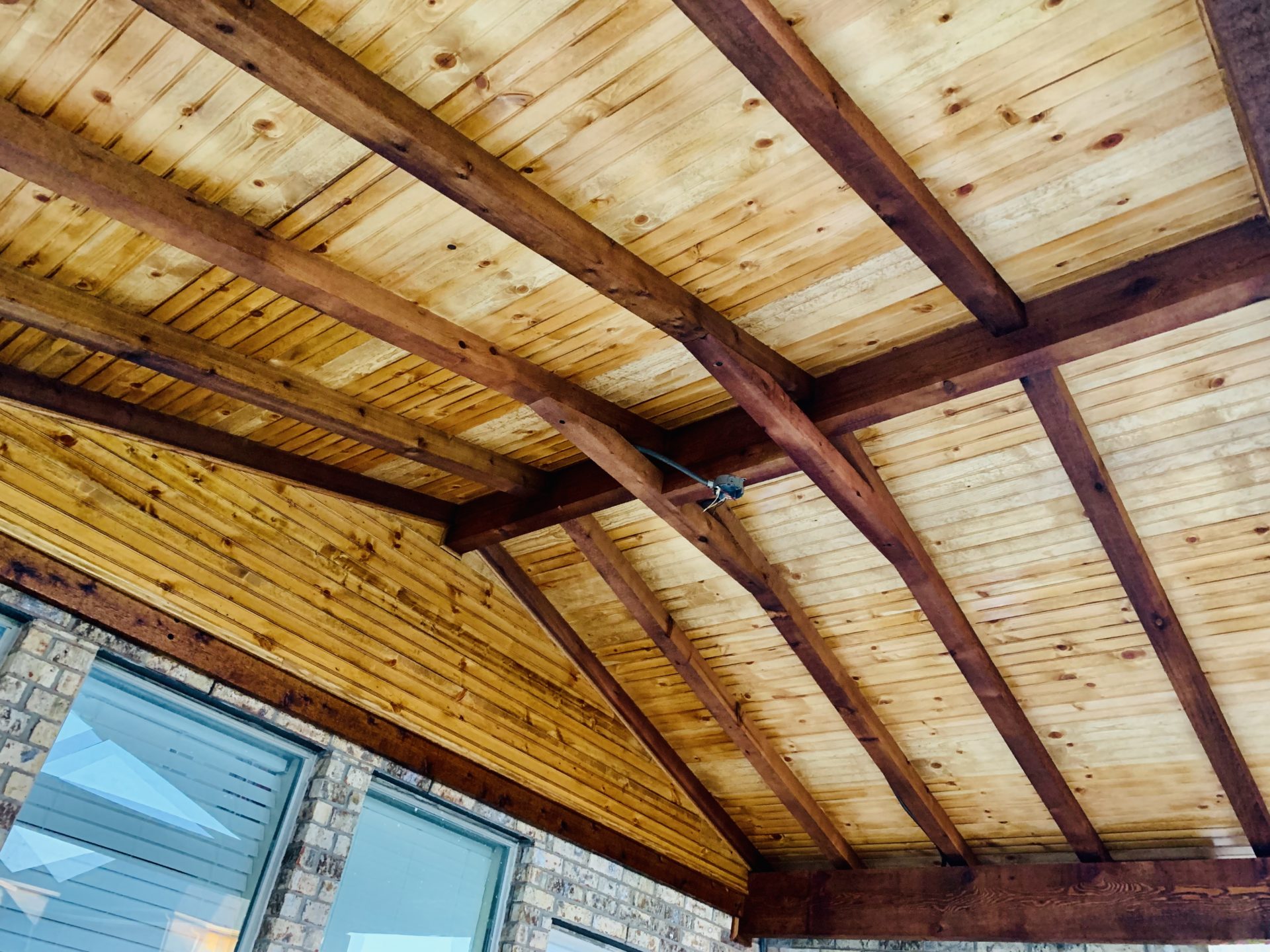 Underneath of a pavilion patio styled roof with beautiful wooden cross beams.