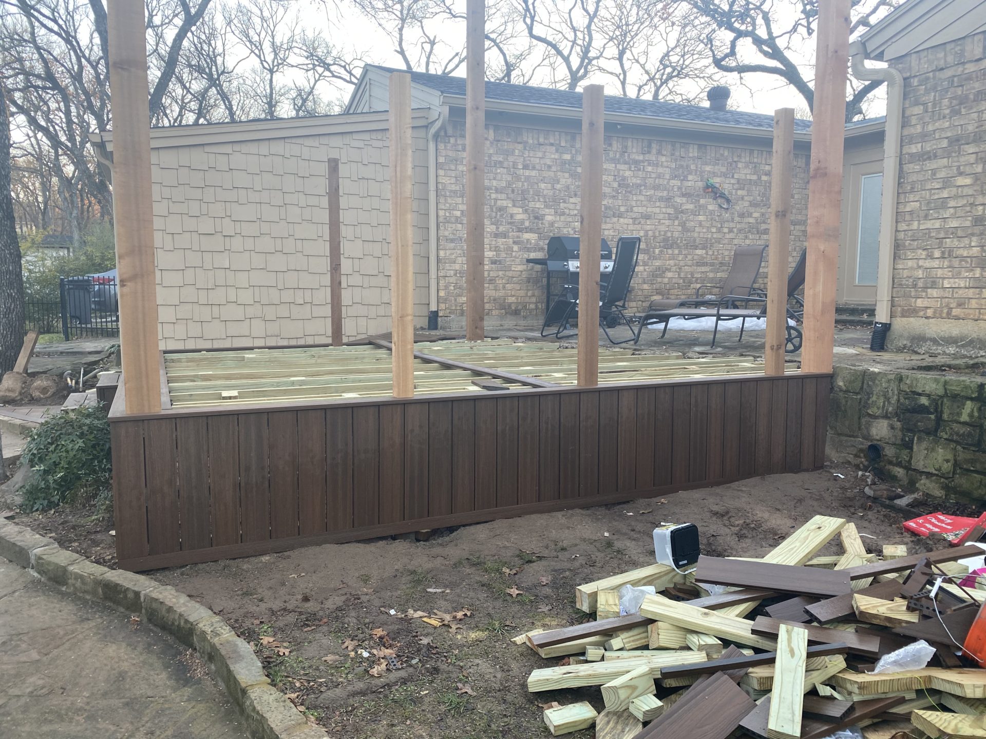 Backyard of a home in Hurst, TX with new patio deck under construction. Patio deck siding is completed.