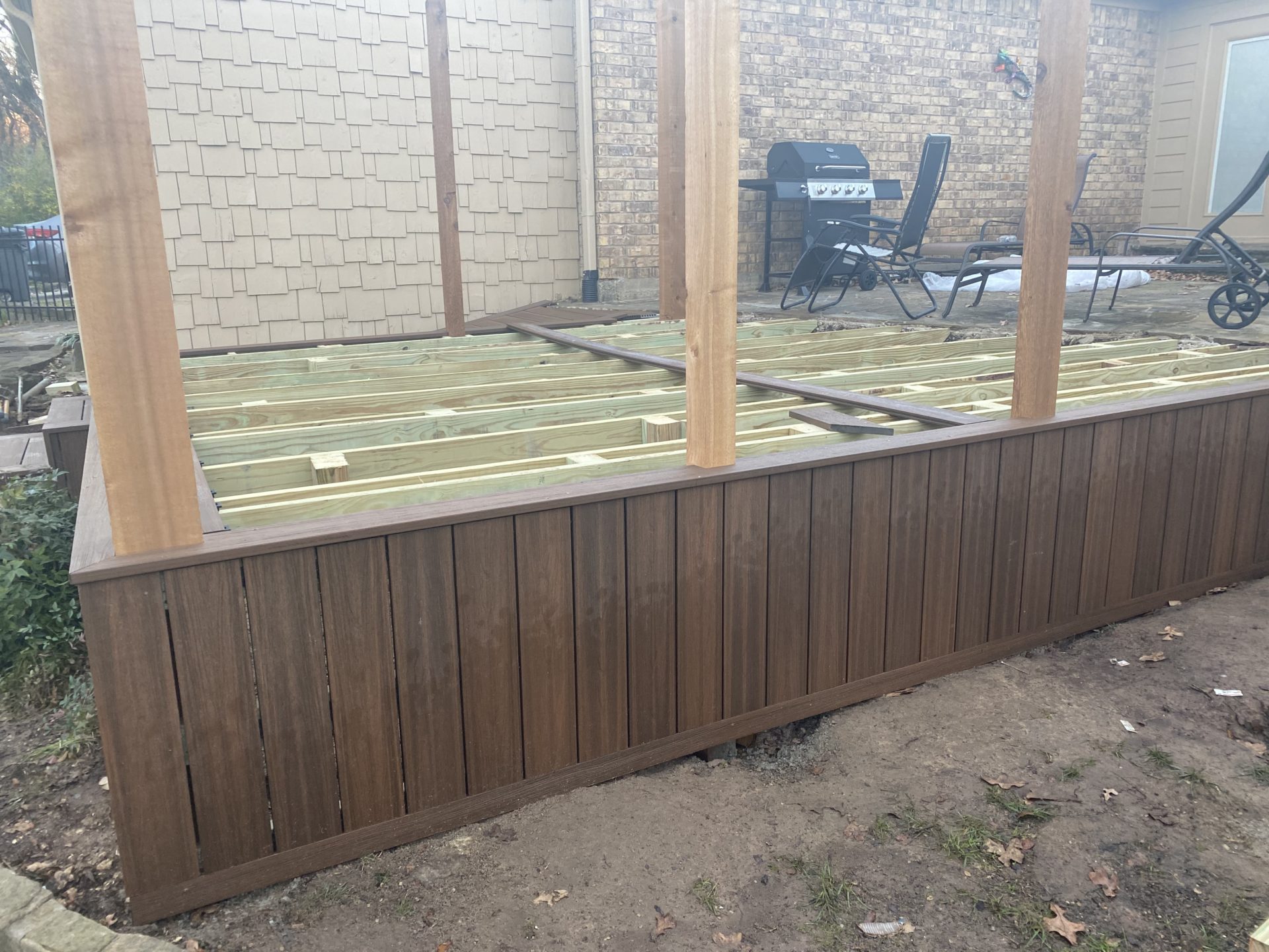 Backyard of a home in Hurst, TX with new patio deck under construction. Patio deck siding is completed and deck is being worked on.