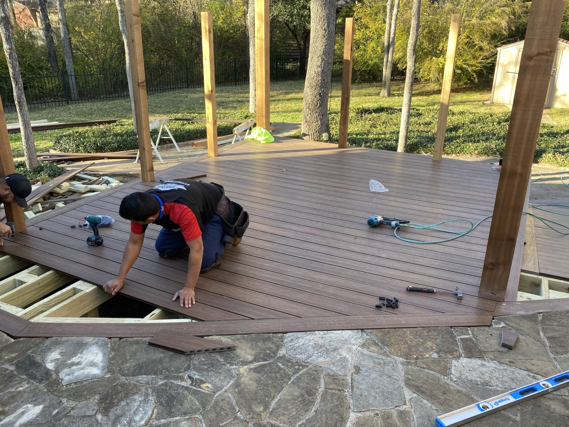 Jenkins Roofing team working on the floor of a backyard patio deck project in Arlington, TX.